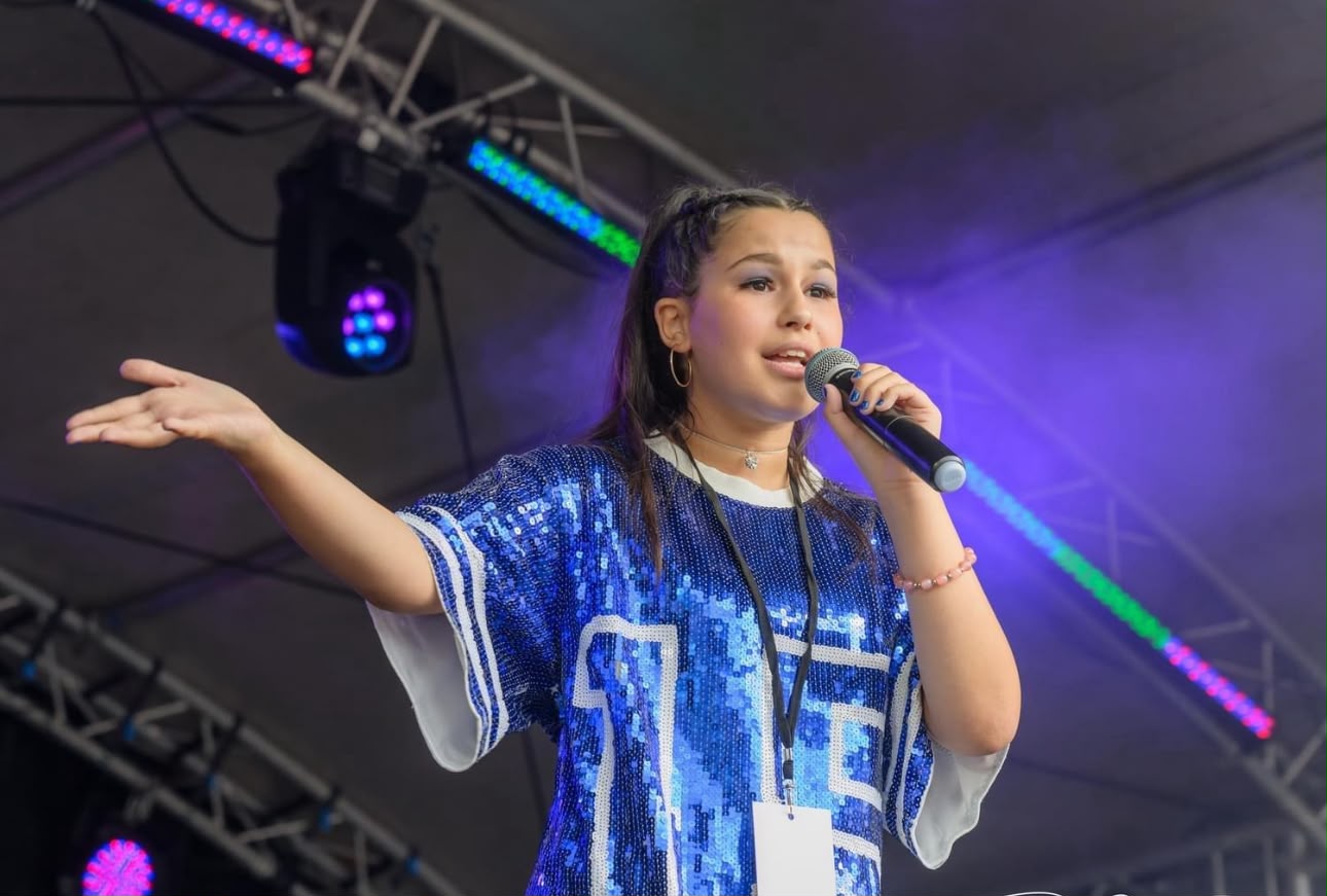 Ella-Grace singing live on an outdoor stage